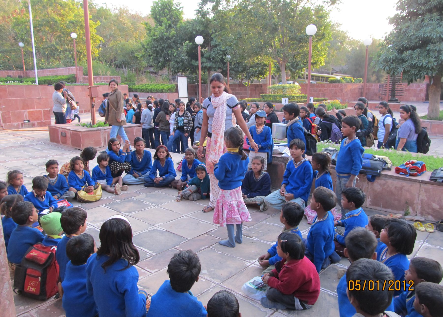 Children of the Museum School seated on the plaza of a Bhopal museum during a lesson